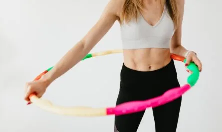 crop sportswoman exercising with gymnastic hula hoop